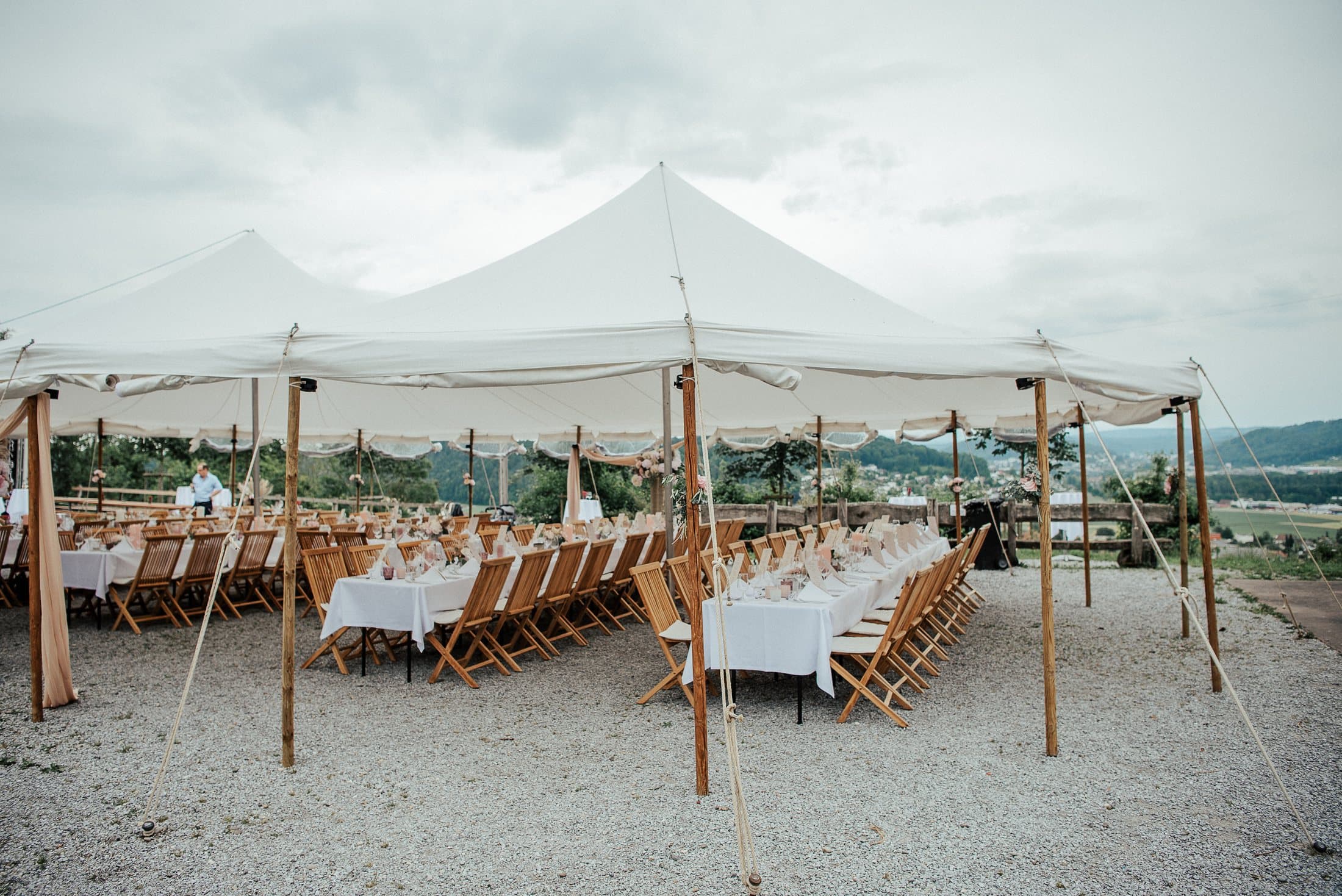Fabric tent with long tables and a view over the valley
