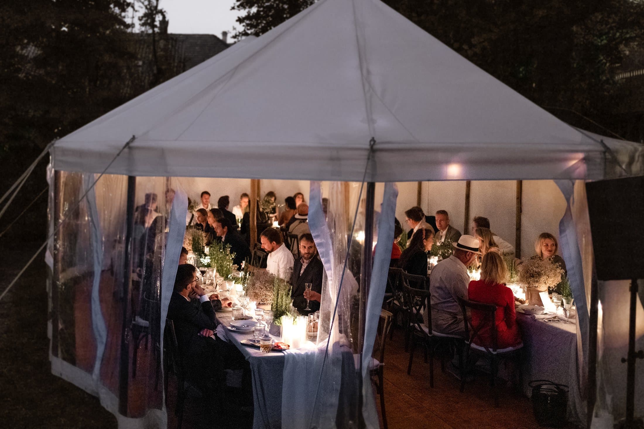 Lit fabric tent in the evening with the wedding party on Lake Como